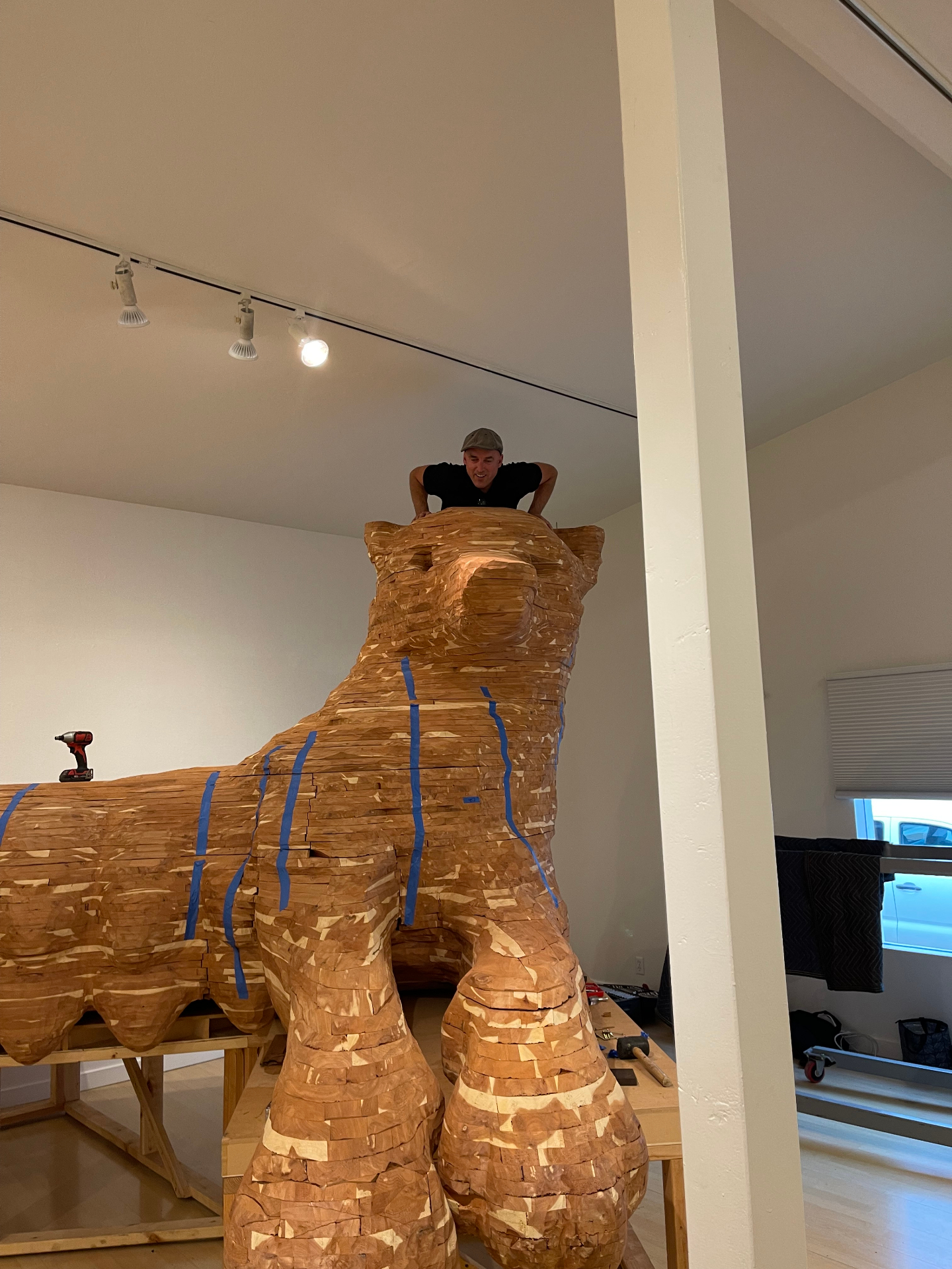 Installer positioning a large carved wood bear sculpture in a gallery space