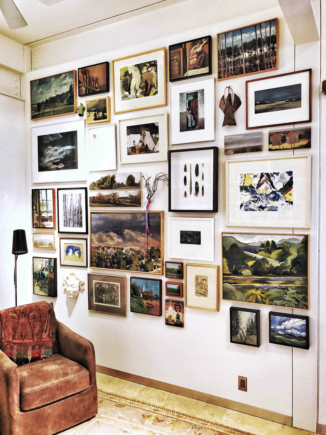 Floor-to-ceiling gallery wall of mixed artwork installed in a Hailey, Idaho home