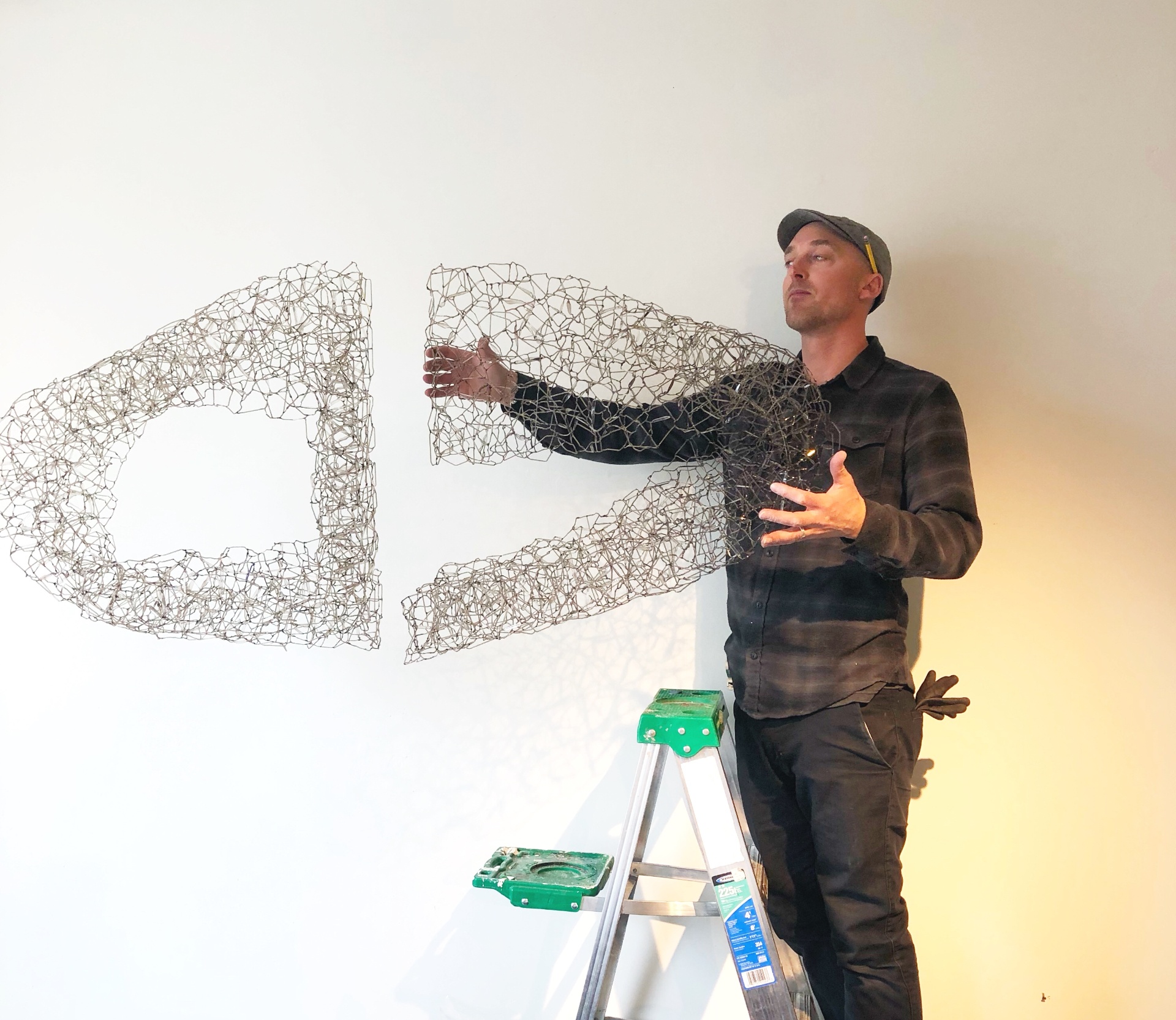 Raven Art Services installing a wall-mounted wire figure sculpture in a private residence